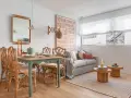 Ideas para decorar un piso pequeño con poco dinero: mesa de comedor de ratán, sofá acogedor y arte de pared llamativo.