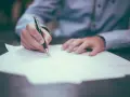 Persona firmando un documento. La pregunta clave es: ¿cuánto tarda en llegar una escritura original?