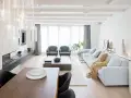 Elegante salón comedor dos ambientes con chimenea, sofás grises, mesa de centro y comedor de madera.