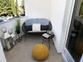 Acogedor rincón con sofá, cojines, mesita y puf amarillo. Dos faroles decoran estas terrazas pequeñas con encanto.