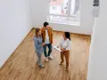 Pareja joven discutiendo con agente inmobiliaria sobre cómo comprar una casa con aportaciones diferentes.