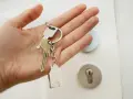 Mano sosteniendo llaves con un llavero de casa. ¡Por fin llega el día cuando pagan la ayuda del alquiler y se puede empezar a soñar con un nuevo hogar!