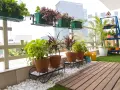 Balcón lleno de plantas en macetas, ideal para decorar terrazas barato. Césped artificial y suelo de madera completan el espacio.
