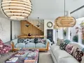 Elegante salón con sofás claros, mesa de centro con libros y lámparas de madera. El minimalismo en casa se refleja en la escalera de madera y la decoración cuidada.