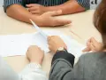 Personas revisando documentos, discutiendo cómo comprar casa sin escrituras.