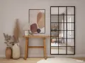 Una elegante entrada para una casa con consola de madera, lámpara, arte abstracto y espejo industrial.