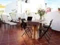 Terraza con tumbonas, mesa y sillas, ideal para uso privativo. Flores y plantas decoran el espacio.