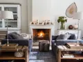 Ideas para decorar la repisa de una chimenea: velas, piñas y un jarrón con ramas secas crean un ambiente acogedor.