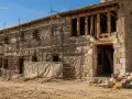 Andamios rodean una casa de piedra en ruinas, demostrando que se puede rehabilitar una casa declarada en ruinas.