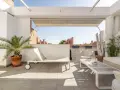Encantadora decoracion terrazas aticos: tumbona, mesa de centro, sillón y plantas crean un oasis urbano.