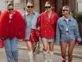 Cuatro mujeres pasean con atuendos llamativos. Una lleva un abrigo rojo voluminoso, otra un conjunto de lentejuelas azules y falda roja. Los colores que pegan con el rojo son el azul y el plateado.