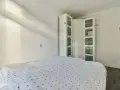 Un armario blanco con puertas de cristal es una solución ideal para saber donde colocar el armario en un dormitorio pequeño, maximizando el espacio.