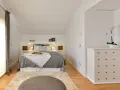 Habitación hermanos poco espacio, con cama doble, alfombra y cómoda blanca.