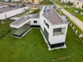Casa moderna con grandes ventanales y tejado plano, rodeada de césped. Se puede poner una casa prefabricada en un terreno urbano como esta.