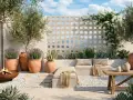 Terraza con asientos, plantas en macetas, un fuego y una pared de bloques decorativa.