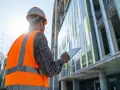 Ingeniero revisa tablet frente a edificio moderno. ¿Qué edificios tienen que pasar la ITE?