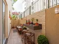 Un balcón acogedor con muebles de madera, plantas y un estante de granito. Ideal para disfrutar de pequeños patios.