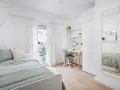 Habitación de estudiante con cama, escritorio, silla y espejo.