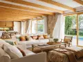 Salones blancos y madera con vigas expuestas, sofás cómodos y vistas a una piscina.