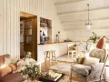 Acogedora buhardilla con encanto, con sofá, sillón estampado, mesa de comedor y cocina abierta.