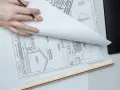 Manos revisando planos de construcción, un detalle que sugiere que se puede escriturar sin cédula de habitabilidad.