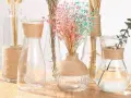 Botellas de cristal decoradas con cuerda, con flores secas y una rama de eucalipto.