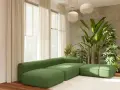 Sofá modular verde pistacho con otomanas a juego, rodeado de exuberantes plantas y cortinas color crema.