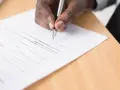 Mano firmando un documento legal. Se puede escriturar una casa a nombre de otra persona mediante este tipo de acuerdos.