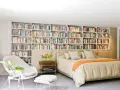 Dormitorio con una pared entera de estanterías llenas de libros, creando un ambiente acogedor en estas casas con biblioteca.