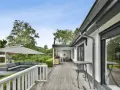 Un porche moderno con muebles de exterior, sombrilla y barbacoa. Ideas para como cerrar un porche y disfrutarlo todo el año.
