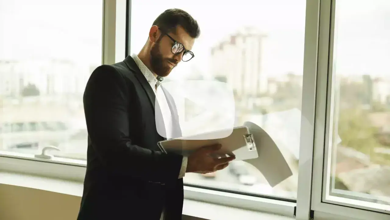 Hombre de negocios revisa documentos junto a la ventana. ¿Es legal pedir un aval bancario para un alquiler?