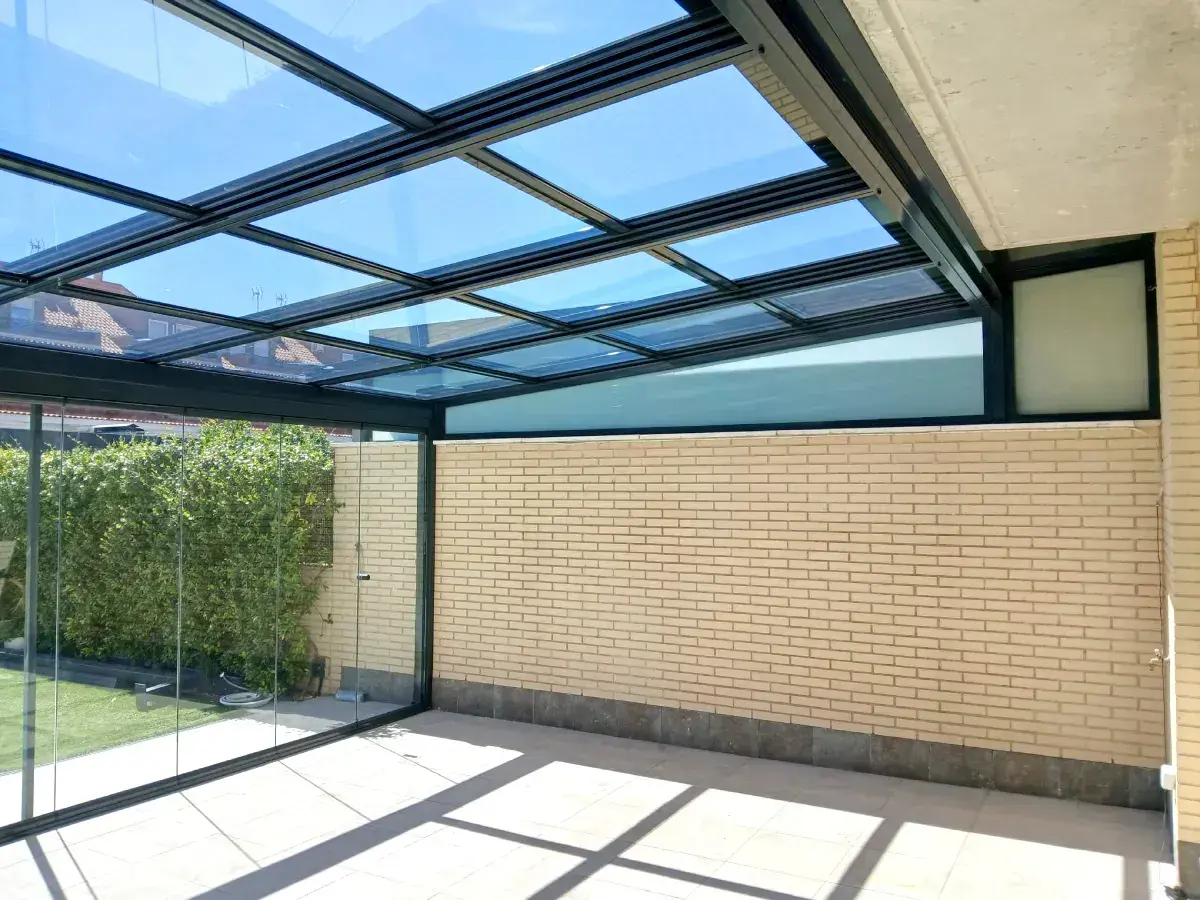 Un moderno montera patio interior con techo de cristal y paredes de ladrillo claro, ideal para disfrutar del exterior.
