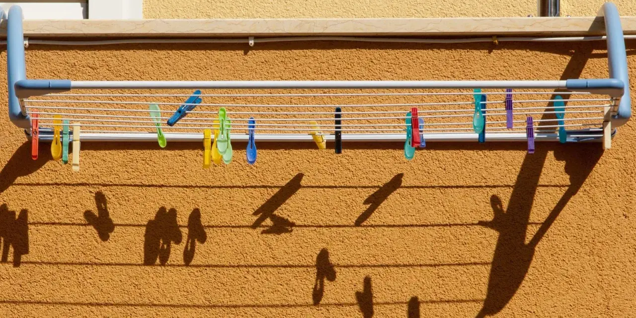 Tendedero exterior con pinzas de colores. Ideas para secar la ropa al sol, creando sombras divertidas en la pared.