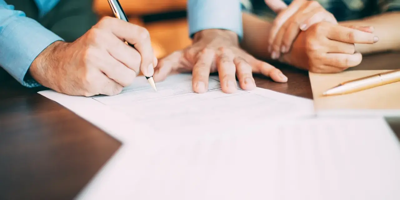 Manos firmando un contrato de alquiler con bolígrafo.
