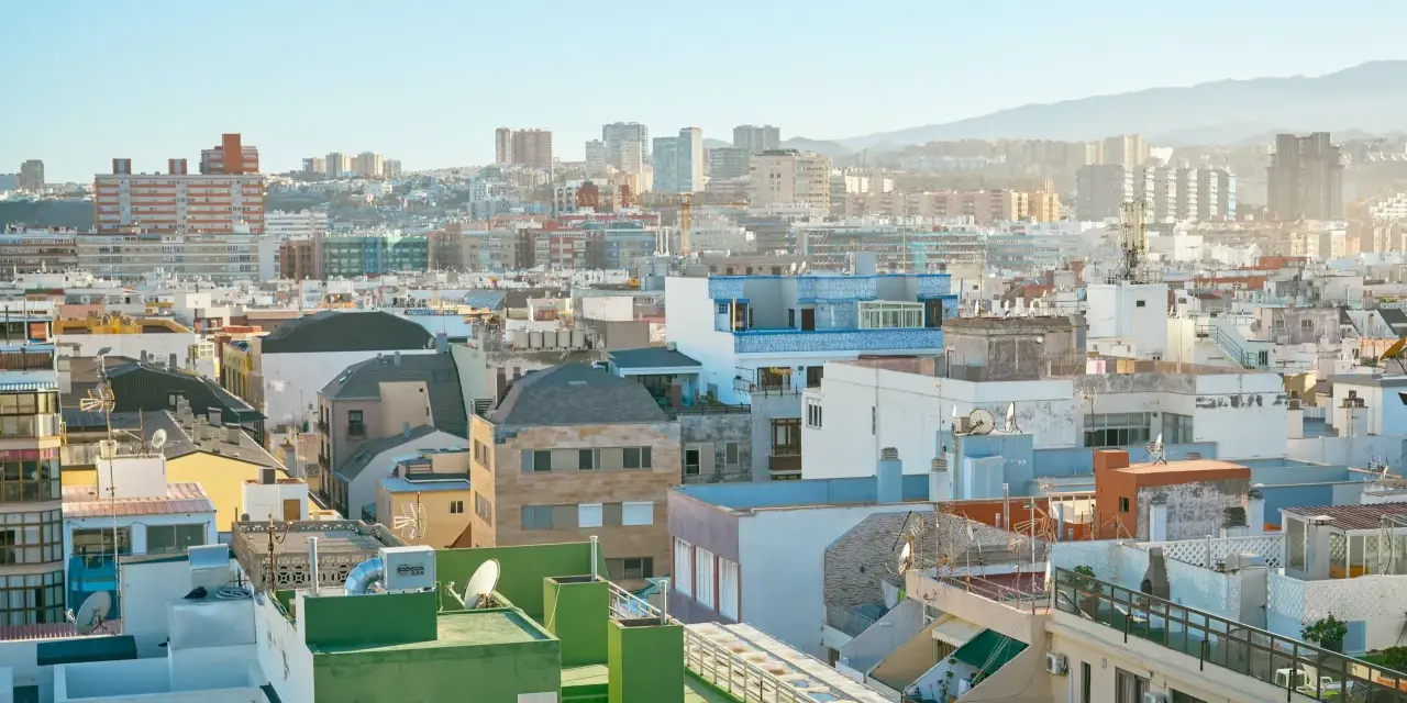 Vista aérea de tejados y edificios de una ciudad española bajo un cielo azul claro.