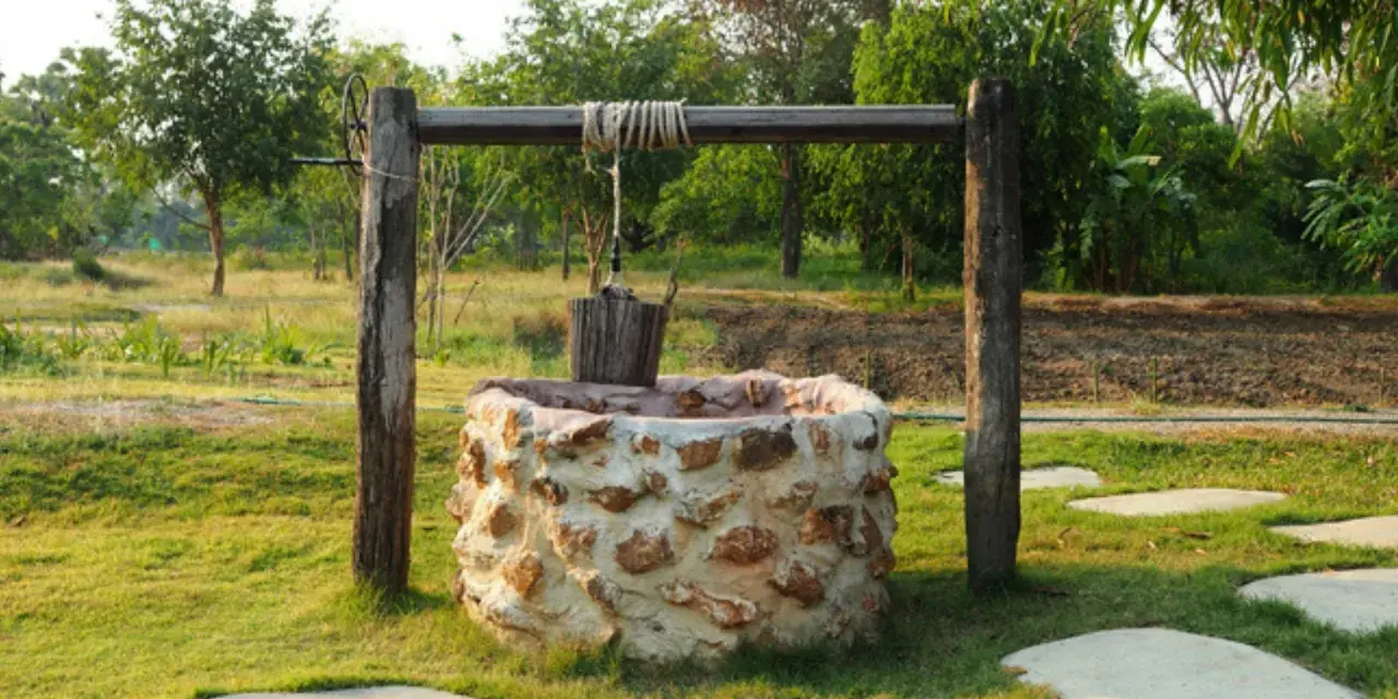 Pozo de piedra con cubo de madera colgando. Interesado en cuanto cuesta hacer un pozo así.