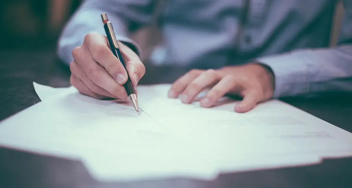 Persona firmando un documento. La pregunta clave es: ¿cuánto tarda en llegar una escritura original?