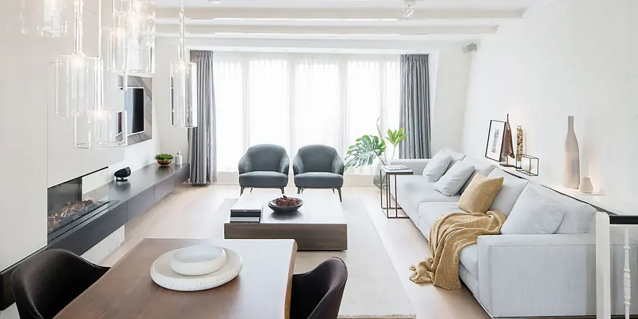 Elegante salón comedor dos ambientes con chimenea, sofás grises, mesa de centro y comedor de madera.