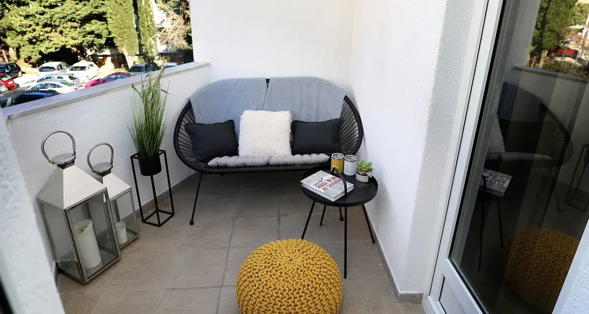 Acogedor rincón con sofá, cojines, mesita y puf amarillo. Dos faroles decoran estas terrazas pequeñas con encanto.