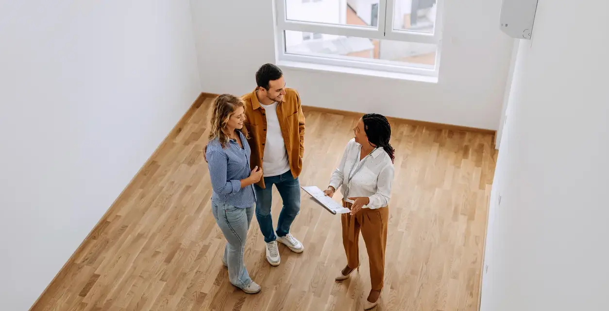 Pareja joven discutiendo con agente inmobiliaria sobre cómo comprar una casa con aportaciones diferentes.