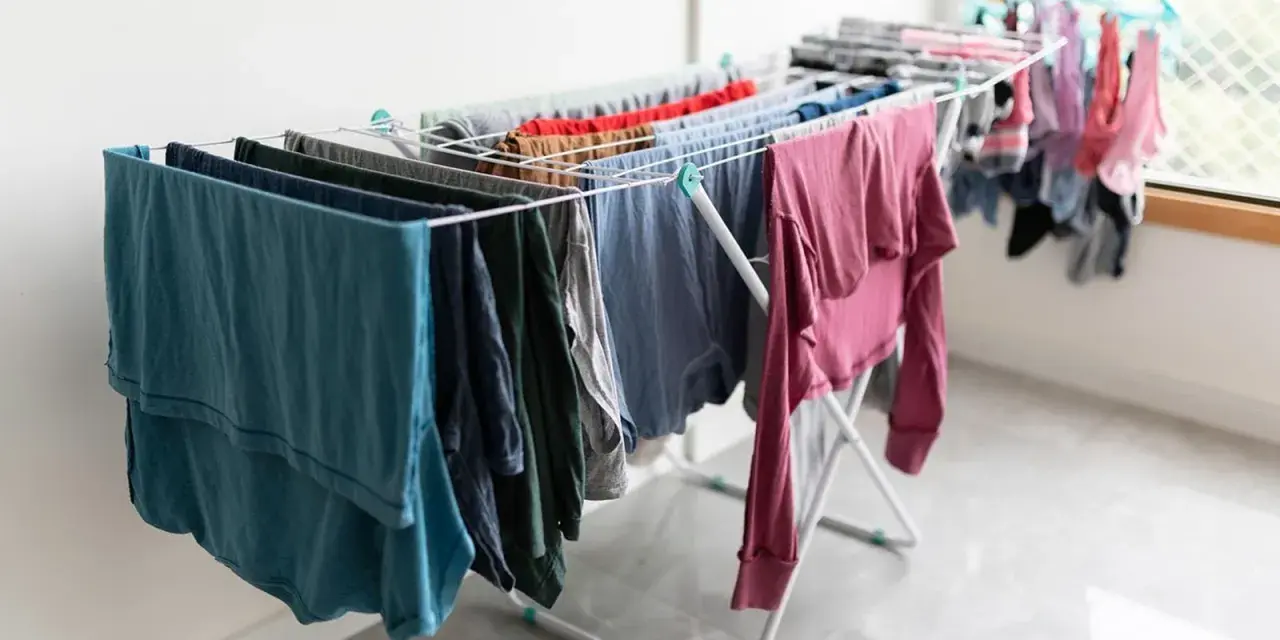 Tendedero desplegado con ropa de varios colores, una solución práctica para tender la ropa en un piso sin terraza.