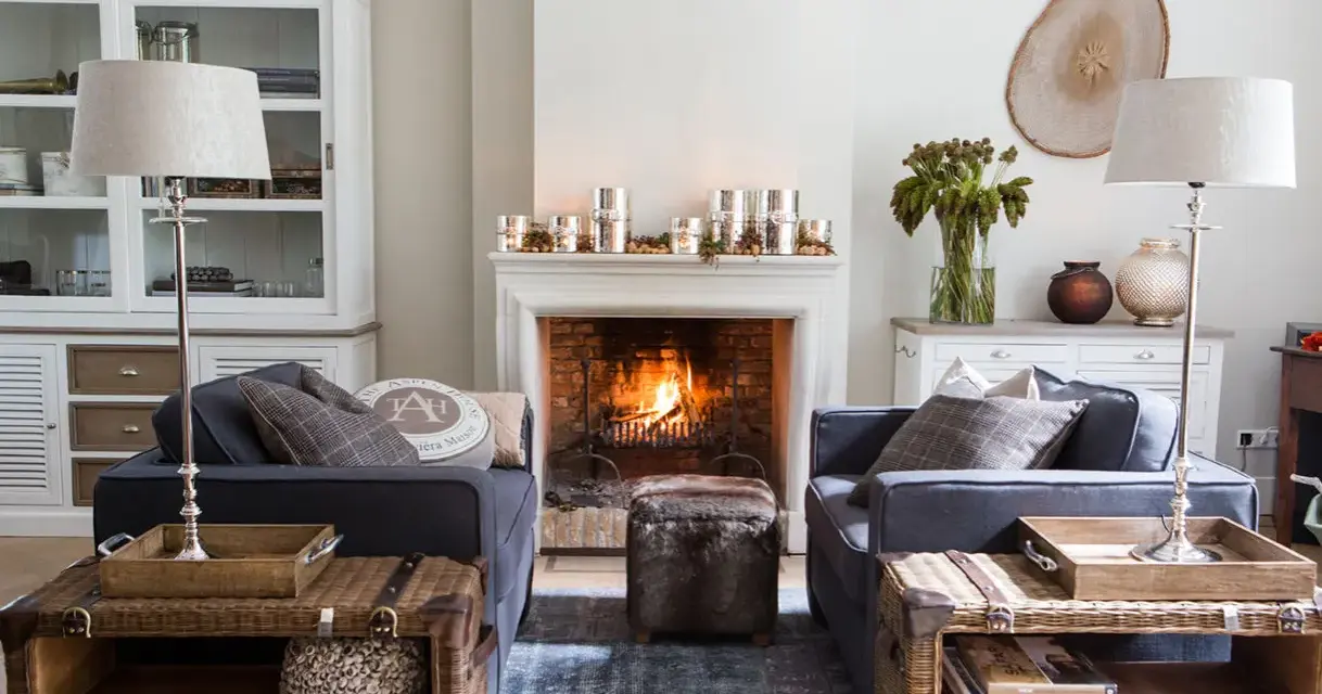 Ideas para decorar la repisa de una chimenea: velas, piñas y un jarrón con ramas secas crean un ambiente acogedor.