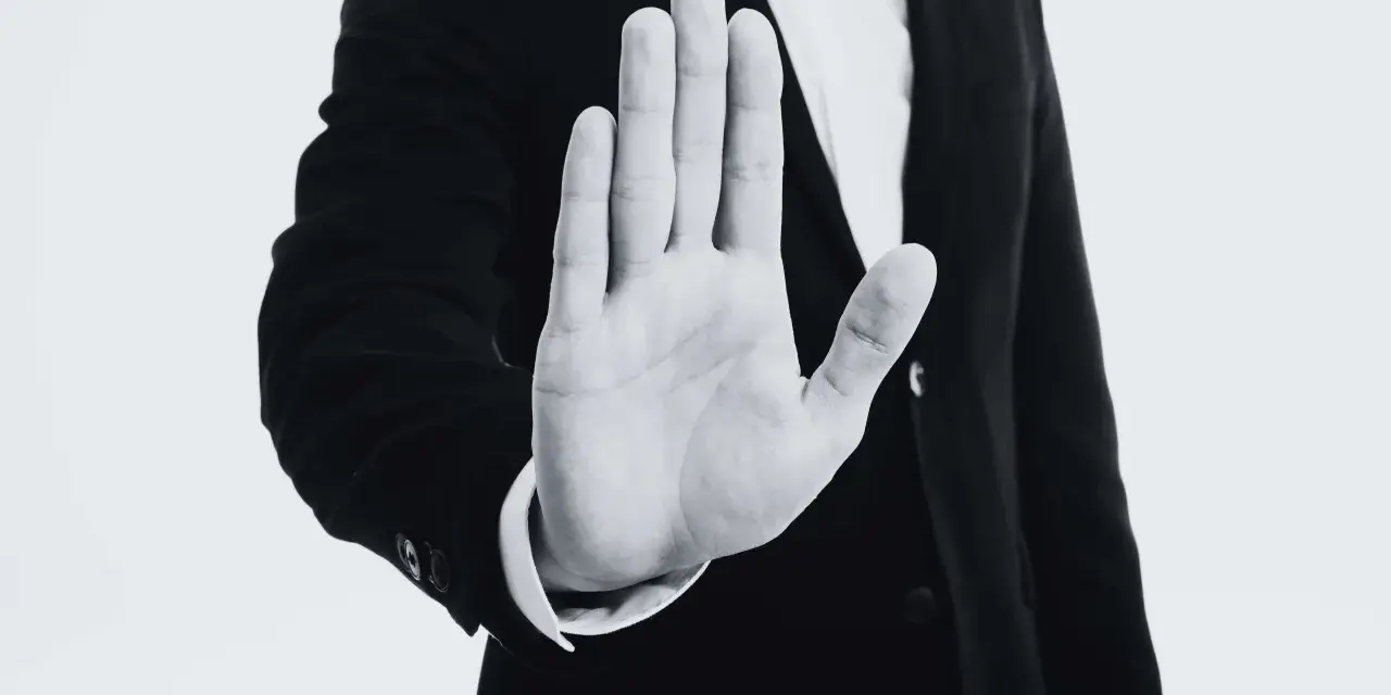 Mano extendida en señal de alto, con un traje oscuro. Representa el derecho de reversión, un límite claro.