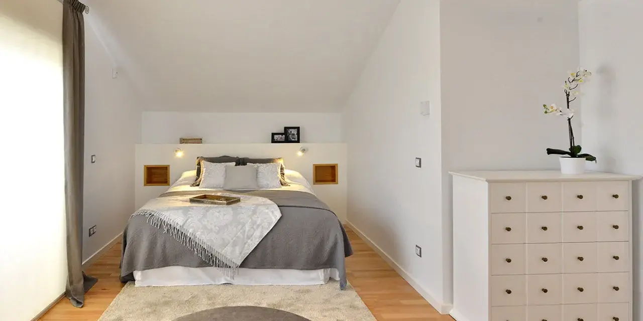 Habitación hermanos poco espacio, con cama doble, alfombra y cómoda blanca.