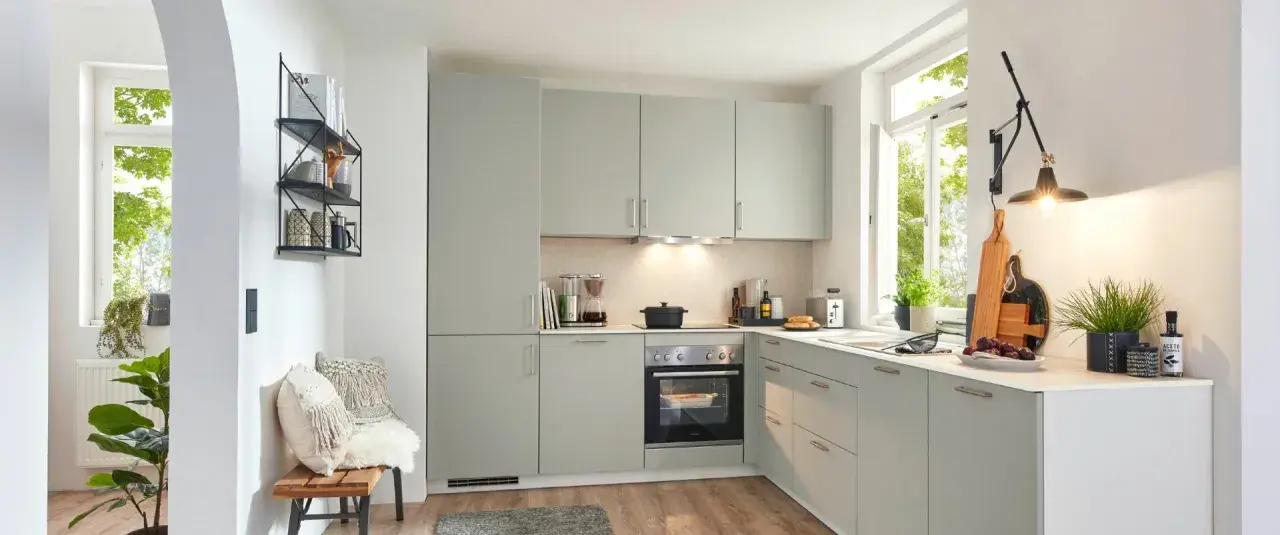 Moderna cocina de obra con armarios grises, electrodomésticos integrados y una ventana luminosa. Perfecta para crear tus platos favoritos.