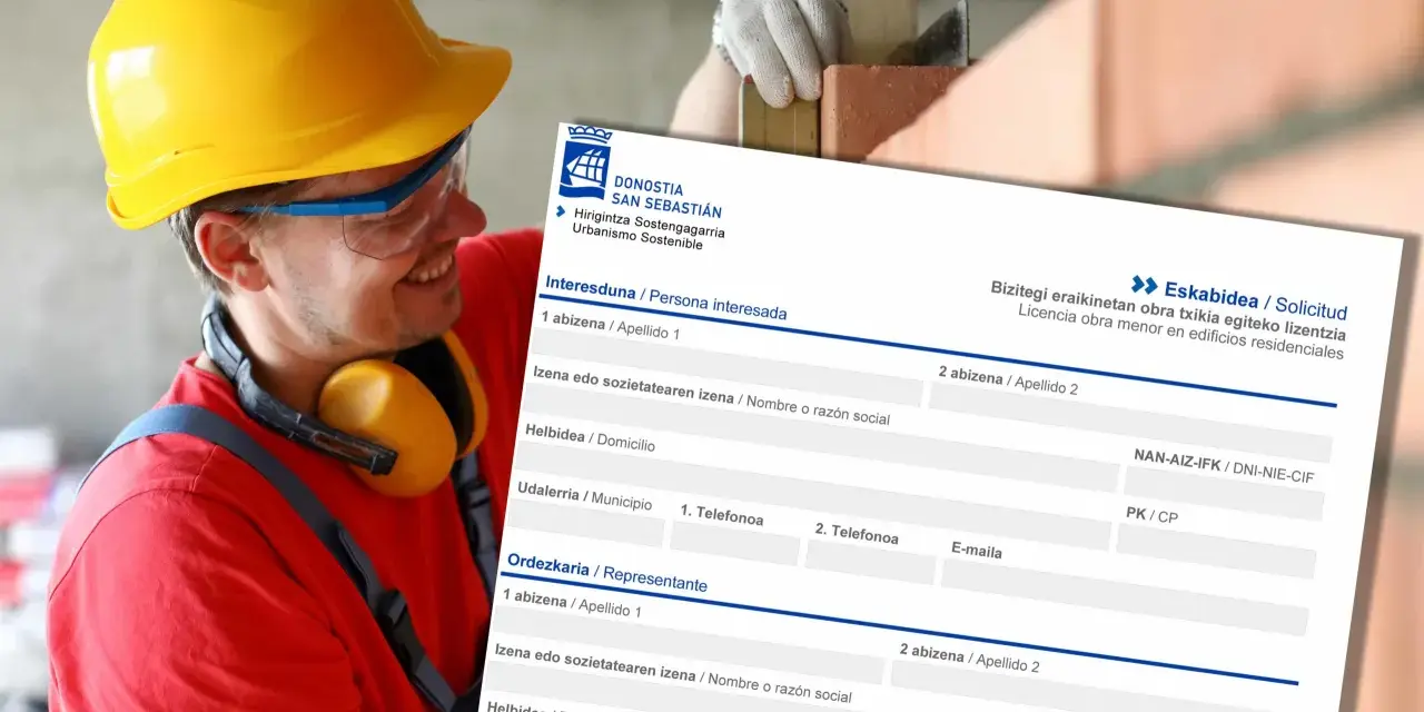 Obrero con casco amarillo sonríe mientras revisa un formulario de solicitud de licencia de obra menor en edificios residenciales.