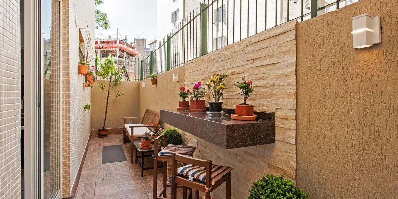 Un balcón acogedor con muebles de madera, plantas y un estante de granito. Ideal para disfrutar de pequeños patios.