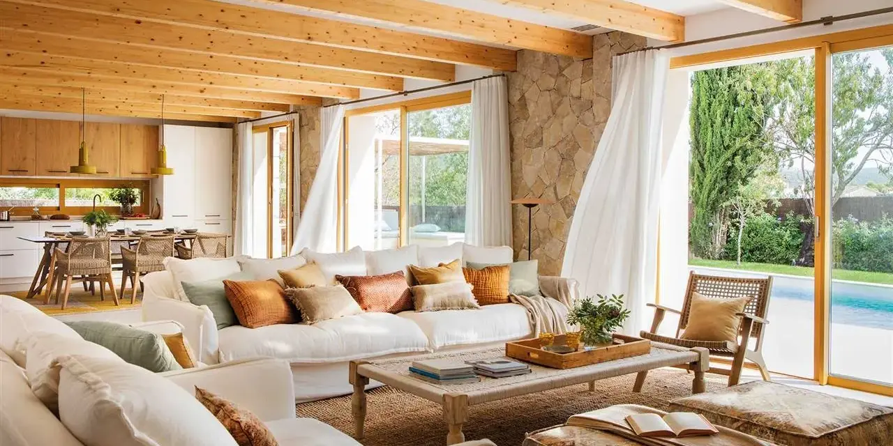 Salones blancos y madera con vigas expuestas, sofás cómodos y vistas a una piscina.