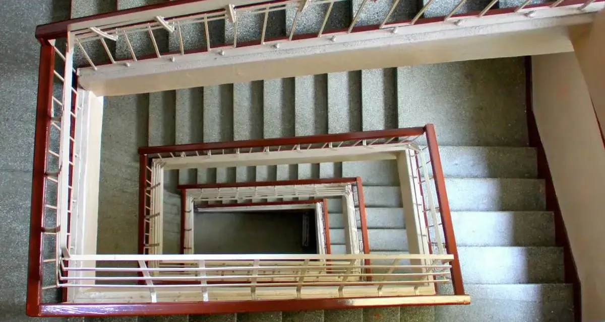 Vista cenital de un **rellano edificio** con escaleras en espiral, barandillas de metal y hormigón.