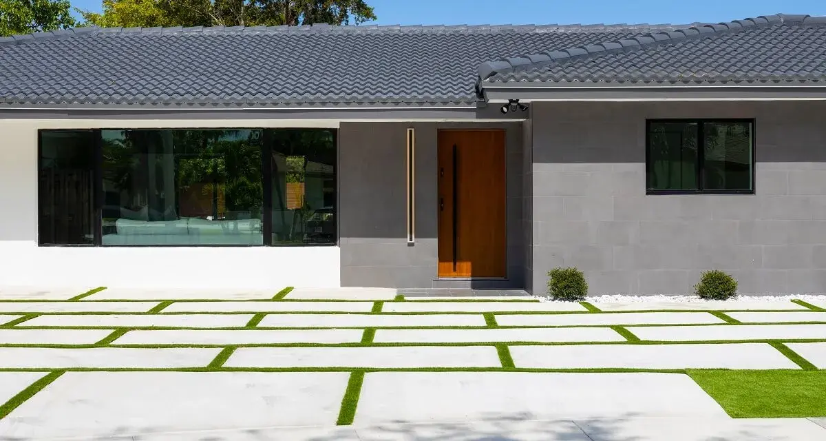 Casa moderna con entrada de madera y ventanal. El camino de acceso combina cemento y césped, ideal si me separo y quiero quedarme el piso.